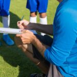 Soccer coach planning strategy with young players on sunny field