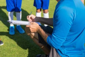 Soccer coach planning strategy with young players on sunny field